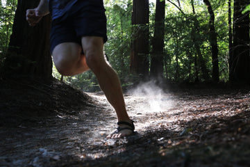 Person running on a forest path with smoke or dust in the air